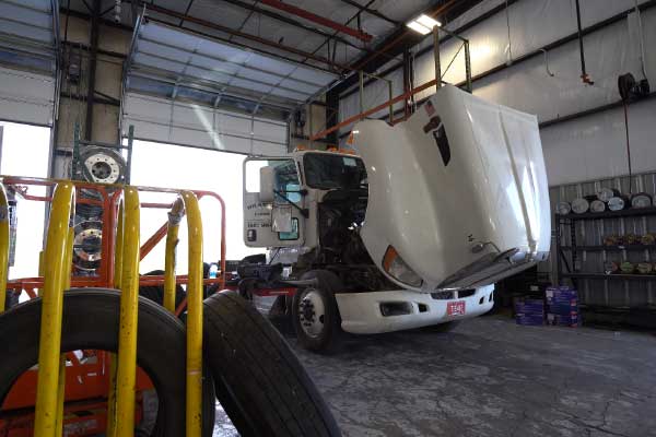 white semi truck being worked on with the hood open